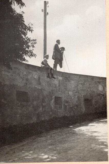 Ein altes Bild von einem Fotografen, der auf einer Mauer steht, neben ihm sitzt ein Junge