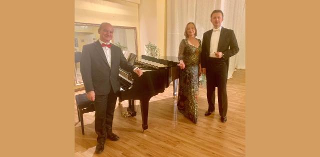 3 Personen stehen an einem Flügel