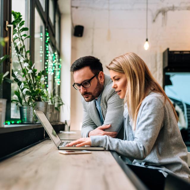 Zwei Personen arbeiten an Laptop