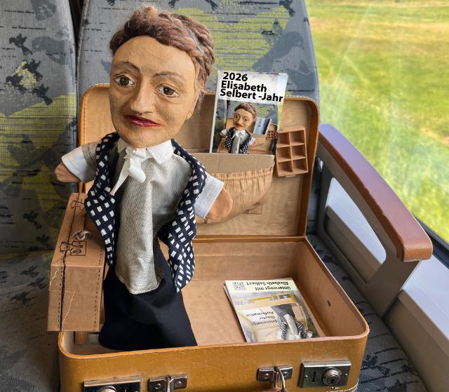 Eine Handpuppe in einem Koffer und Flyer. 