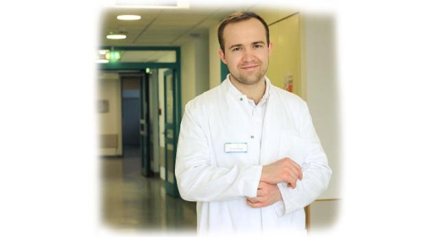 Ein Arzt im weißem Kittel steht im Krankenhausflur