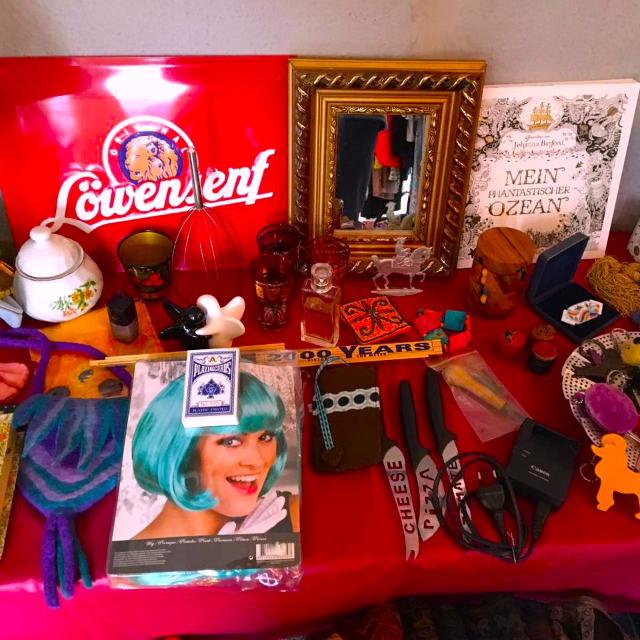 Foto von vielen zum Verkauf aufgestellten Kleinigkeiten: Bilder, Schilder, Selbstgemachtes, Perücken,...