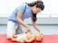 Kinderkrankenpflegerin zeigt Herzdruckmassage an Puppe