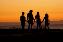 Silouette einer Familie mit vier Personen vor einem Sonnenuntergang. 