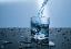 Ein Wasserglas, das gerade mit Wasser gefüllt wird.