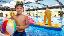 Junge mit Wasserball steht vor einem Schwimmbecken