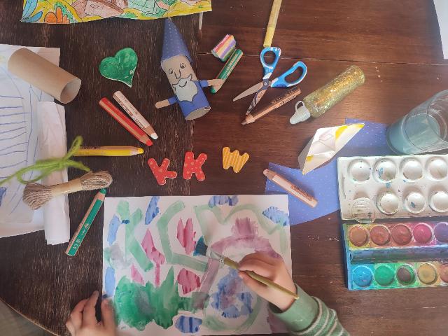 Kinderhände und Bastelutensilien um die Buchstaben KKW angeordnet.