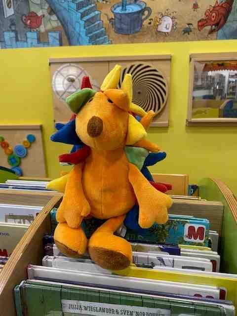 Maskottchen Kibby sitzt auf ein paar Bilderbüchern.