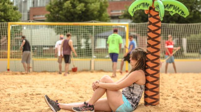 Frau sitzt auf dem Unistrand und lehnt an eine aufblasbare Palme