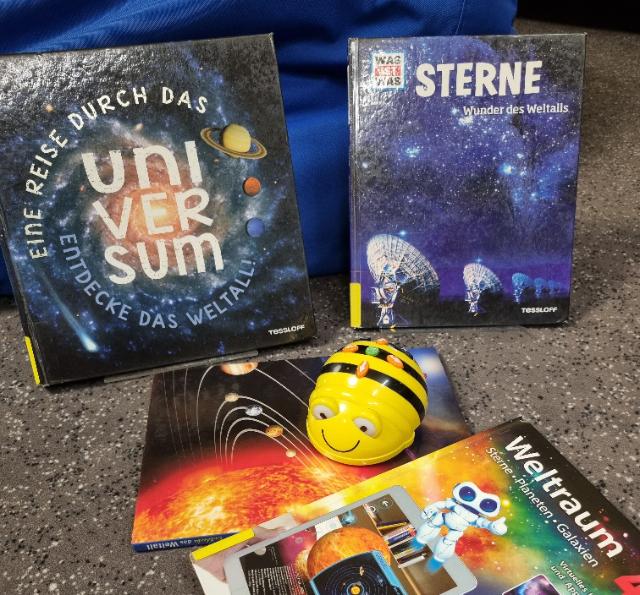 Eine Roboterbiene steht vor Sachbüchern über den Weltraum.
