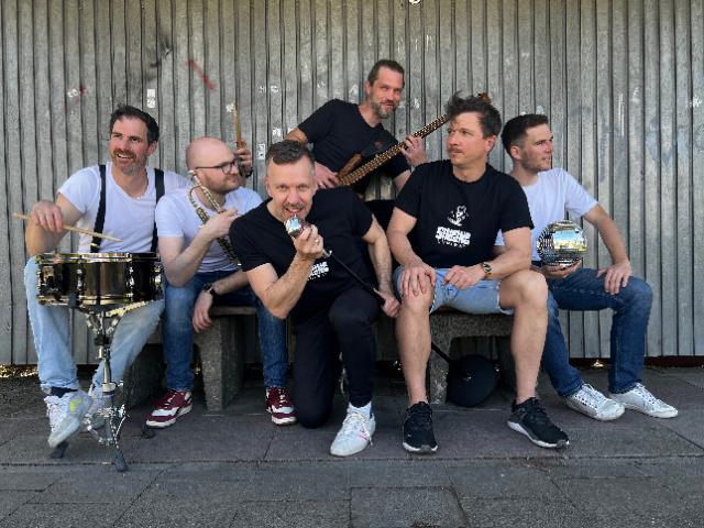 6 Musiker posen mit ihren Instrumenten