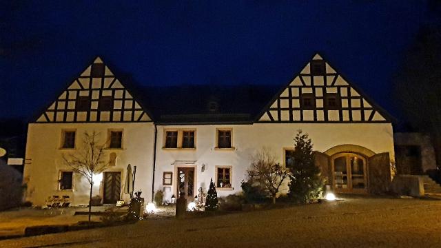Aussenansicht des Gutshofs Mengersdorf bei Nacht mit stimmungsvoller Beleuchtung. 