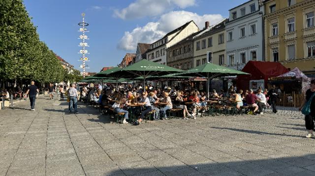 Menschen sitzen auf Bierbänken auf dem Stadtparkett
