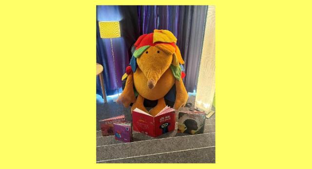 Ein großer Plüschigel liest in einem Buch