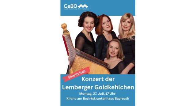 Vier Frauen sitzen hinter einer Bandura und lächeln in die Kamera. Die Frauen tragen festliche Kleidung