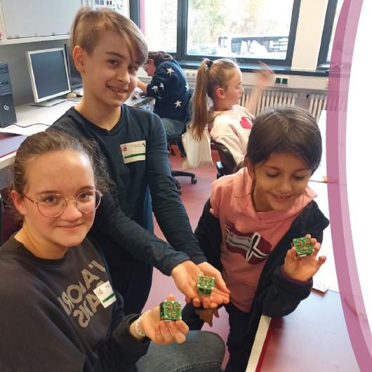 3 Kinder präsentieren stolz ihr fertiges Projekt für die Kamera