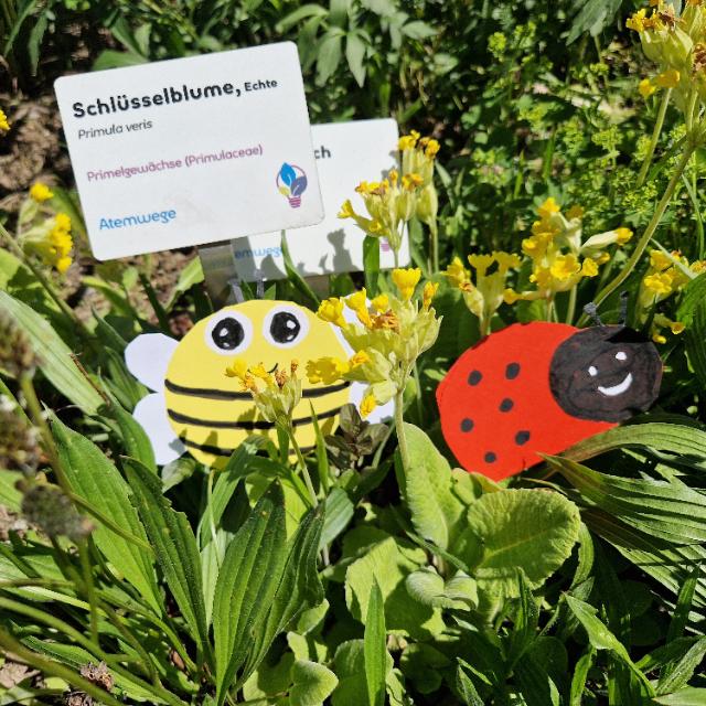 Vor einer gelben Blume befinden sind eine Biene und ein Marienkäfer aus Papier.
