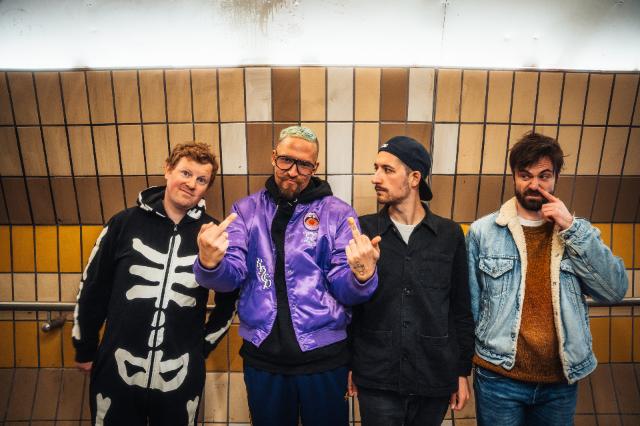 Vier Männer stehen vor einer Wand.