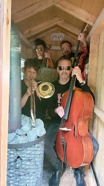 Eine Gruppe von Musiker*innen sitzt in einer kleinen Sauna und schaut in die Kamera.