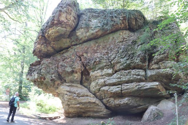 Gewaltiger Felsen Weg mitten im Wald. Daneben stehend ein Mann mit Rücksack.