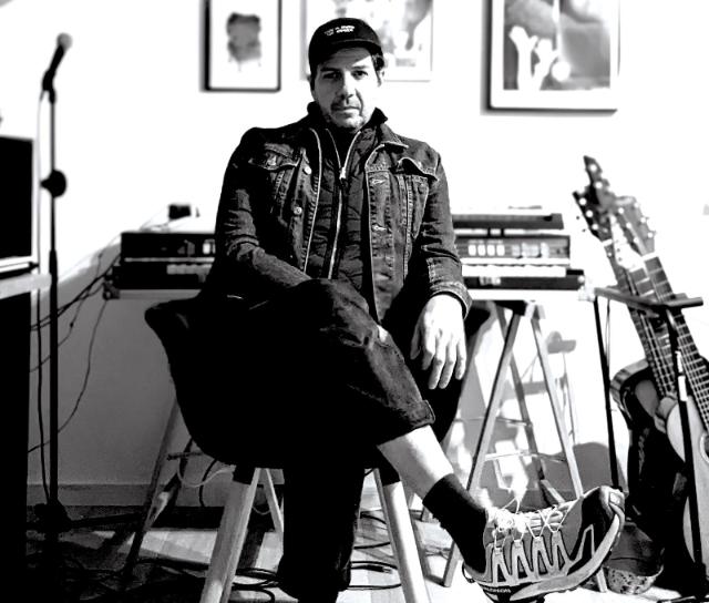 Dirk Puchte sitzt in seinem Musikstudio mit überschlagenen Beinen vor seinen Synthesizer und elektronischen Geräten