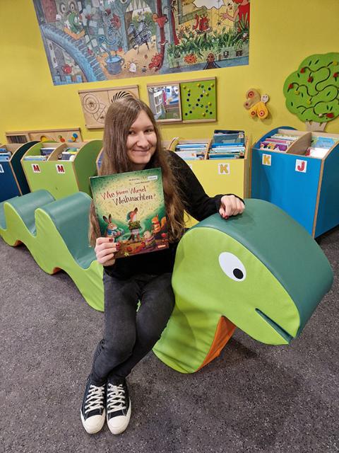 Frau sitzt mit Buch in der Hand auf Schaumstoffschlange.
