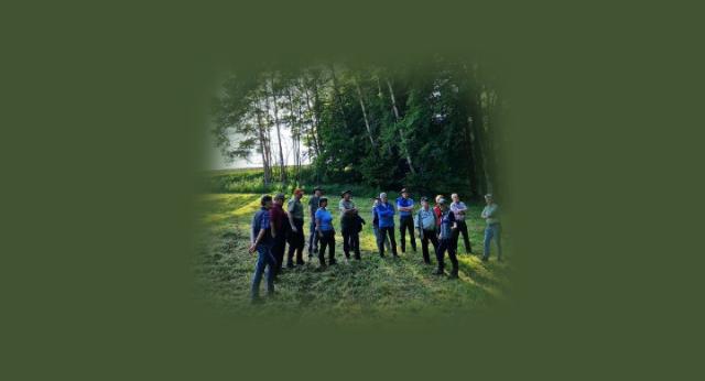 Ein Gruppe Personen steht auf einer Wiese vor einem Wald