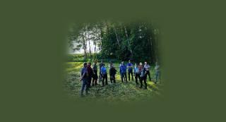 Ein Gruppe Personen steht auf einer Wiese vor einem Wald