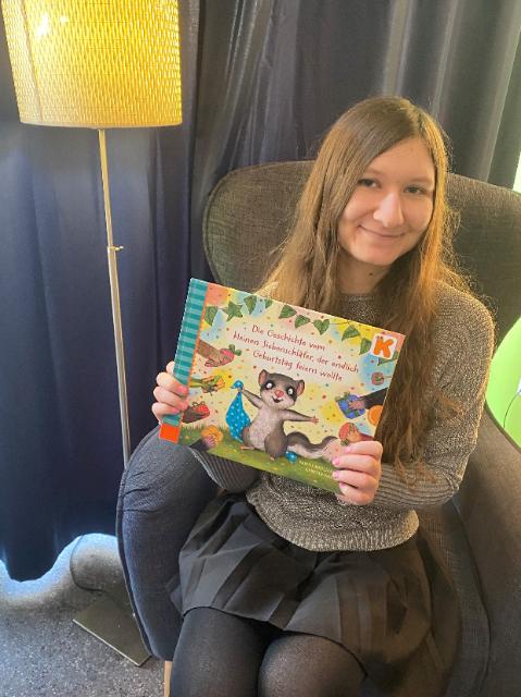 Eine junge Frau mit langen braunen Haaren und einem Buch in der Hand