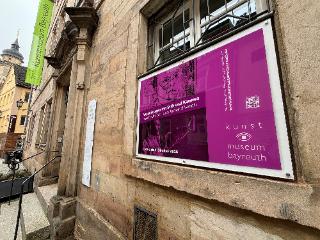 Blick auf das Kunstmuseum mit einem Plakat an der Wand zur Ausstellung Augenzeugen