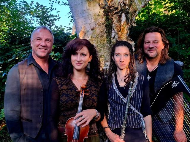 die gesamte Band mit Instrumenten vor einem Baum