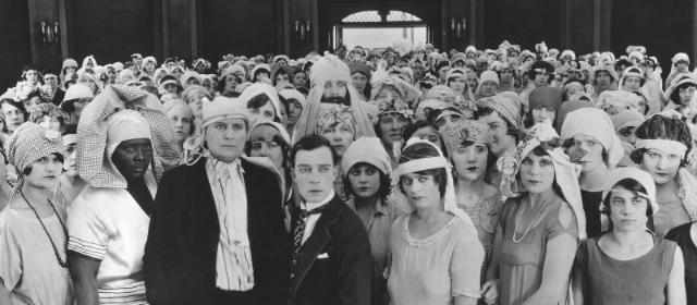 Buster Keaton steht in einer Menge von Bräuten