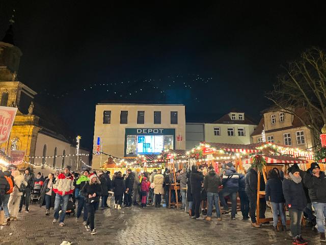 Menschen schlendern am Abend durch den Christkindlesmarkt Bayreuth