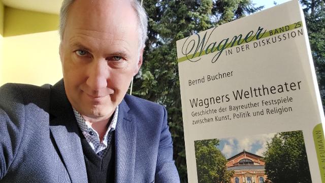 Mann zeigt ein Buch in die Kamera