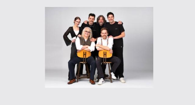 Eine Band mit sechs Mitgliedern, vier stehend, zwei sitzend